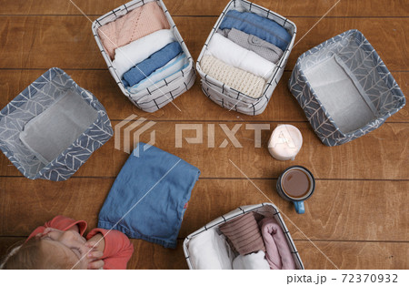 A group of organic cotton clothing laid out on a wooden background is ready to be folded into white baskets.The concept of closet organization.using the komari method. A group of organic cotton clothing laid out on a wooden background is ready to be folded into white baskets.The concept of closet organization.using the komari method. 72370932