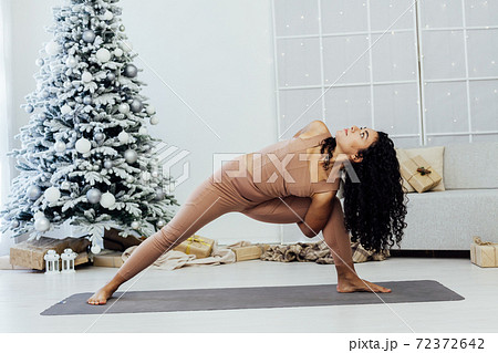 Woman yoga asana gymnastics at Christmas tree New Year Woman yoga asana gymnastics at Christmas tree New Year 72372642