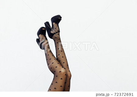 beautiful slender women's legs in black tights on a white background beautiful slender women's legs in black tights on a white background 72372691
