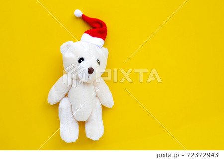 Toy bear wearing a santa hat on yellow background. Christmas holidays concept Toy bear wearing a santa hat on yellow background. Christmas holidays concept 72372943