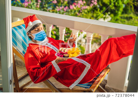 cheerful santa man in a medical mask hold exotic fruit. healthy gift. christmas during coronavirus COVID 19. bearded man healthy eating. merry christmas. happy new year. xmas gifts and presents 72378044