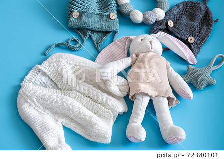 Knitted baby clothes and accessories on a blue background . 72380101