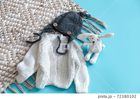 Knitted baby clothes and accessories on a blue background . 72380102