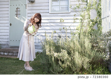 庭で植物に水やりをする若い女性の写真素材
