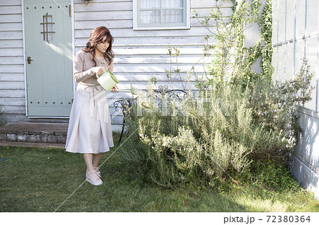 庭で植物に水やりをする若い女性の写真素材