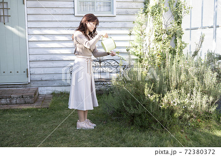 庭で植物に水やりをする若い女性の写真素材