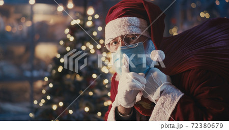 Santa Claus in mask walking quietly near Christmas tree Santa Claus in mask walking quietly near Christmas tree 72380679