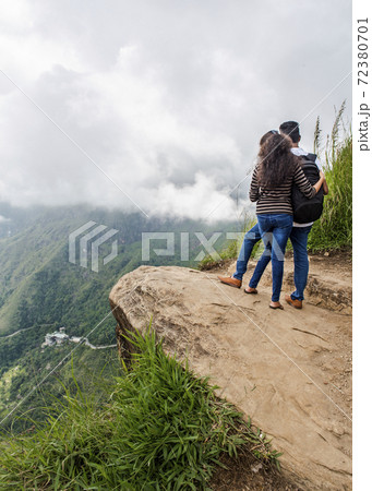 A couple of young people on the edge of a mountain cliff admiring valley on the island of Sri Lanka A couple of young people on the edge of a mountain cliff admiring valley on the island of Sri Lanka 72380701