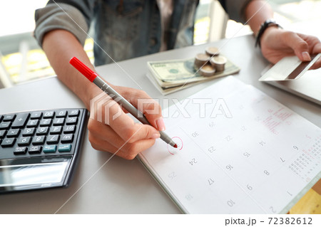 businesswoman paying monthly and holding credit cards and writing on calendar businesswoman paying monthly and holding credit cards and writing on calendar 72382612