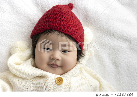 白いセーターと赤いニット帽を着た赤ちゃんの顔 0歳 生後5か月 女の子 の写真素材