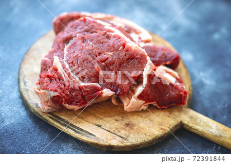 Raw meat beef steak on wooden cutting board on bluish black background. Top view. Close up. 72391844