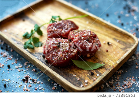 Raw meat beef steak on wooden tray, coarse pink Himalayan salt, black pepper, bay leaf, cilantro Raw meat beef steak on wooden tray, coarse pink Himalayan salt, black pepper, bay leaf, cilantro 72391853