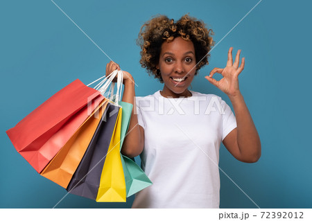 Smiling african woman with shopping bags showing ok gesture. 72392012