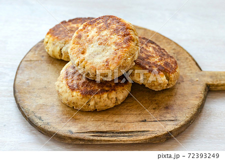 Homemade cottage cheese pancakes syrniki stack on round wooden cutting board, white table background Homemade cottage cheese pancakes syrniki stack on round wooden cutting board, white table background 72393249