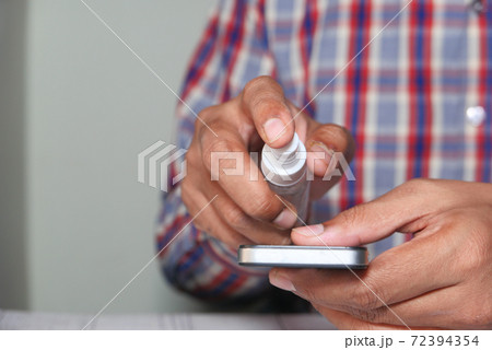 man hand cleaning mobile phone display. 72394354