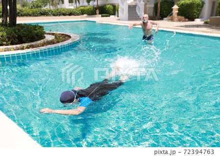 happy elderly caucasian husband and elderly asian wife swimming in pool during retirement holiday with relaxation and happily on sunny day outdoor happy elderly caucasian husband and elderly asian wife swimming in pool during retirement holiday with relaxation and happily on sunny day outdoor 72394763