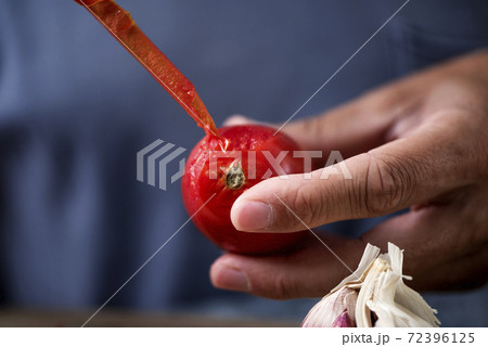 man peeling a scalded tomato man peeling a scalded tomato 72396125