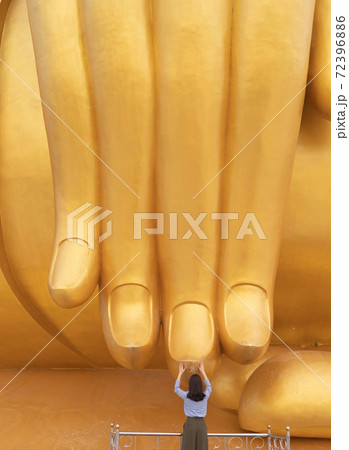 Asian woman Pay respect at the finger of Giant Golden Buddha in Wat Muang in Ang Thong district near Bangkok. Urban town city, Thailand. 72396886