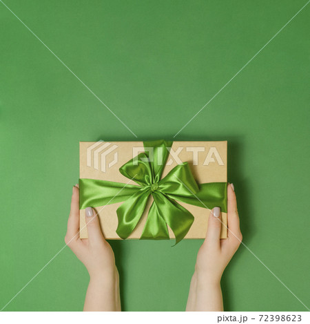 Woman holding present box on green table Woman holding present box on green table 72398623