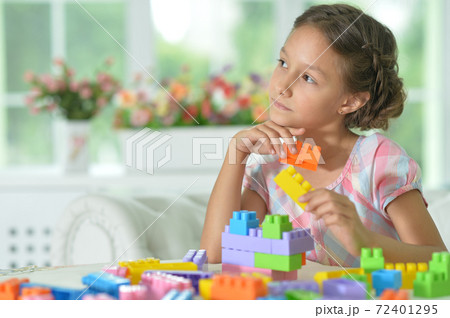 Little girl playing with colorful plastic blocks 72401295