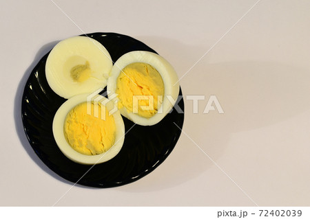 A peeled and cut chicken egg lies on a black ceramic plate, there is a place for an inscription. A peeled and cut chicken egg lies on a black ceramic plate, there is a place for an inscription. 72402039