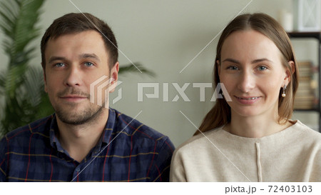 Portrait of a young couple sitting on a sofa. Couple looking at the camera 72403103