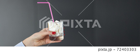 Female hand holds glass with sugar cubes and straw Female hand holds glass with sugar cubes and straw 72403303