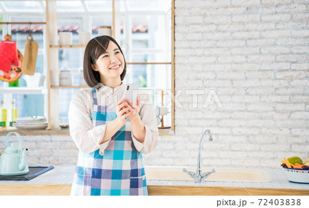 キッチンでスマホを使う若い女性 72403838
