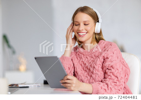 Cheerful female with tablet listening to music. Cheerful female with tablet listening to music. 72404481