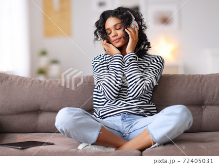 Ethnic female listening to music on sofa. Ethnic female listening to music on sofa. 72405031