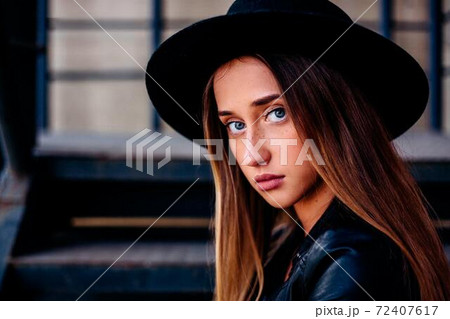 Portrait of a woman in a black hat, freckles on her face, blue eyes, long hair Portrait of a woman in a black hat, freckles on her face, blue eyes, long hair 72407617