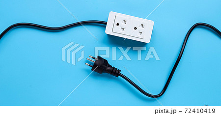 Electrical power strip and plug on blue background. Top view Electrical power strip and plug on blue background. Top view 72410419