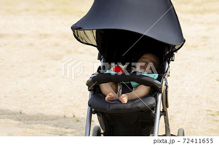 公園で黒いベビーカーに乗って寝ている赤ちゃんとコピースペースの写真素材