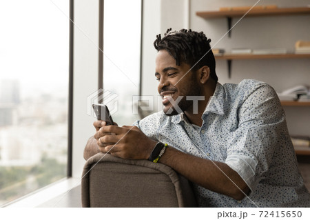Smiling African American man use cellphone texting Smiling African American man use cellphone texting 72415650