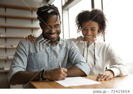 Happy biracial couple sign deal in office Happy biracial couple sign deal in office 72415654