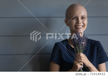 Head shot smiling hairless woman cancer patient holding flowers 72418432