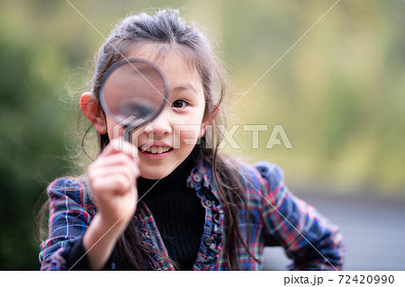 虫眼鏡でこちらを見る少女 72420990