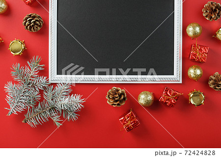 New Year's frame with New Year's toys, fir branches and gifts in an environment on a red background. 72424828
