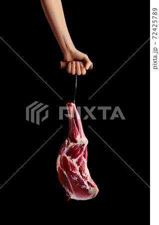 Hand of a butcher holds raw leg of lamb 72425789