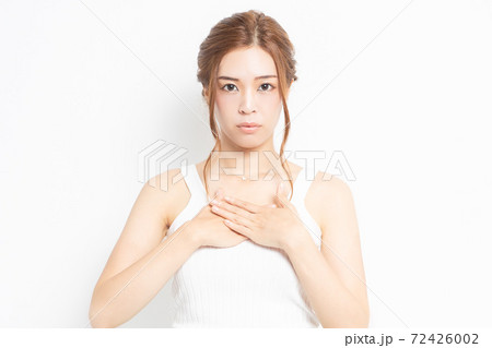 胸に手を当てる若い女性 72426002