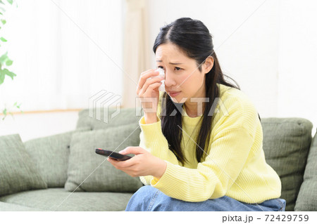 涙を拭く女性 72429759