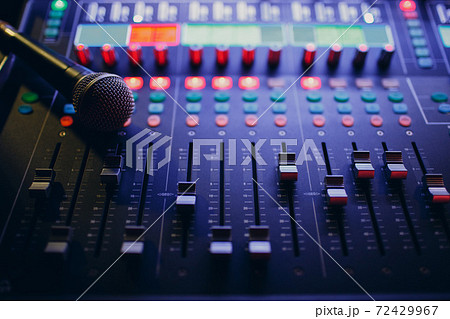 Mixing console and microphone, hand equalizing audio sound channels in night club Mixing console and microphone, hand equalizing audio sound channels in night club 72429967