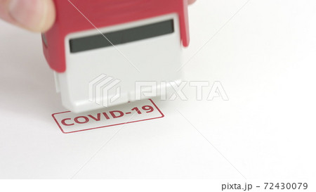 Putting red COVID-19 rubber stamp on the paper, close-up shot Putting red COVID-19 rubber stamp on the paper, close-up shot 72430079