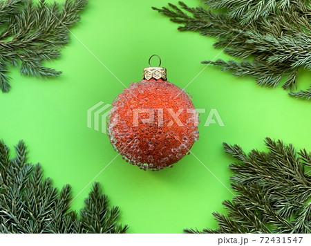 A template for your projects on a festive theme in the form of a red Christmas ball on a green background and coniferous twigs around the edges. Happy New Year and Christmas concept. 72431547