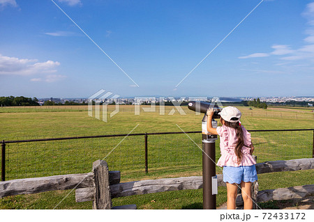 望遠鏡で広大な景色を眺める女の子の後ろ姿 72433172