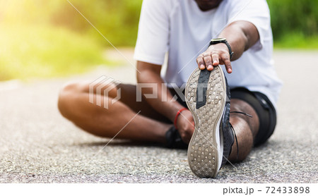 sport runner black man wear watch he sitting pull toe feet stretching legs and knee 72433898