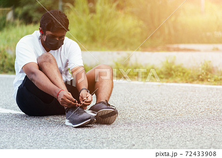 sport runner black man wear watch sitting he trying shoelace running shoes 72433908