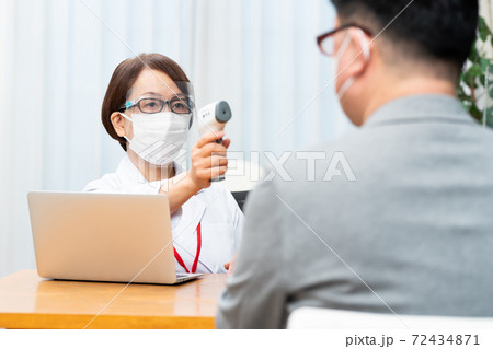 フェイスシールドを付けて検温をする看護師 72434871