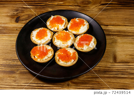Tartlets with red caviar and soft cheese on a wooden table 72439514