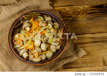 Delicious marinated mushrooms with carrot, onion and spices in ceramic bowl on wooden table. Top view Delicious marinated mushrooms with carrot, onion and spices in ceramic bowl on wooden table. Top view 72439543